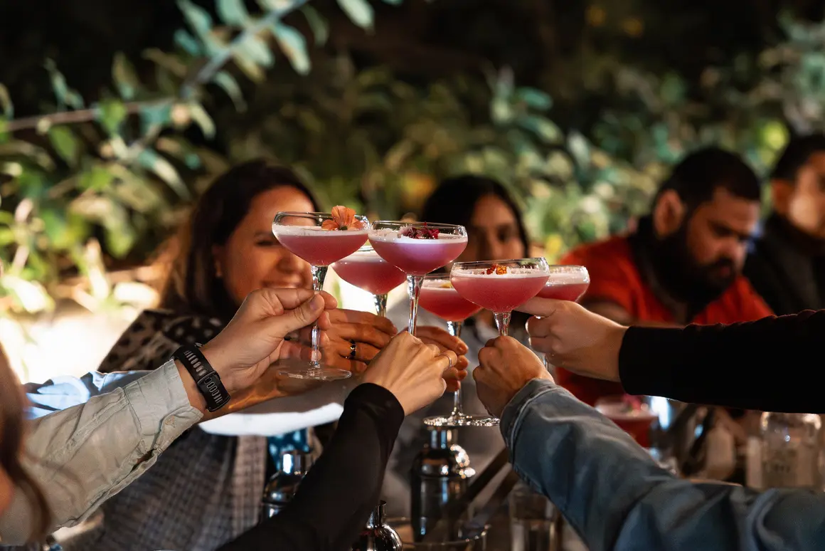Personas brindando con cócteles de 2 Cuervos